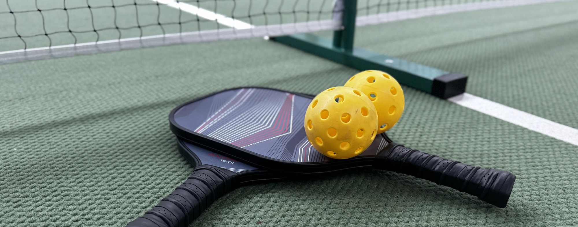 2 Pickleball-Schläger mit 2 gelben Bällen